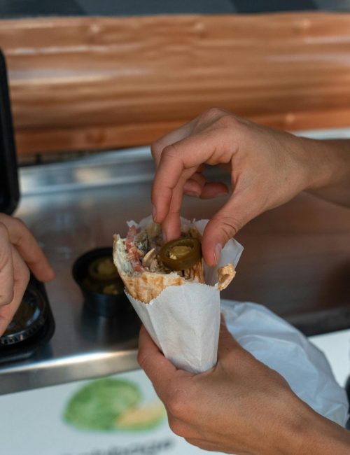 Two people enjoying a jalapeno-topped shawarma from a street vendor.